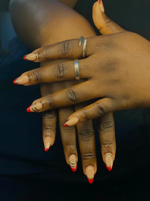 Almond nails with red French tips and gold detail